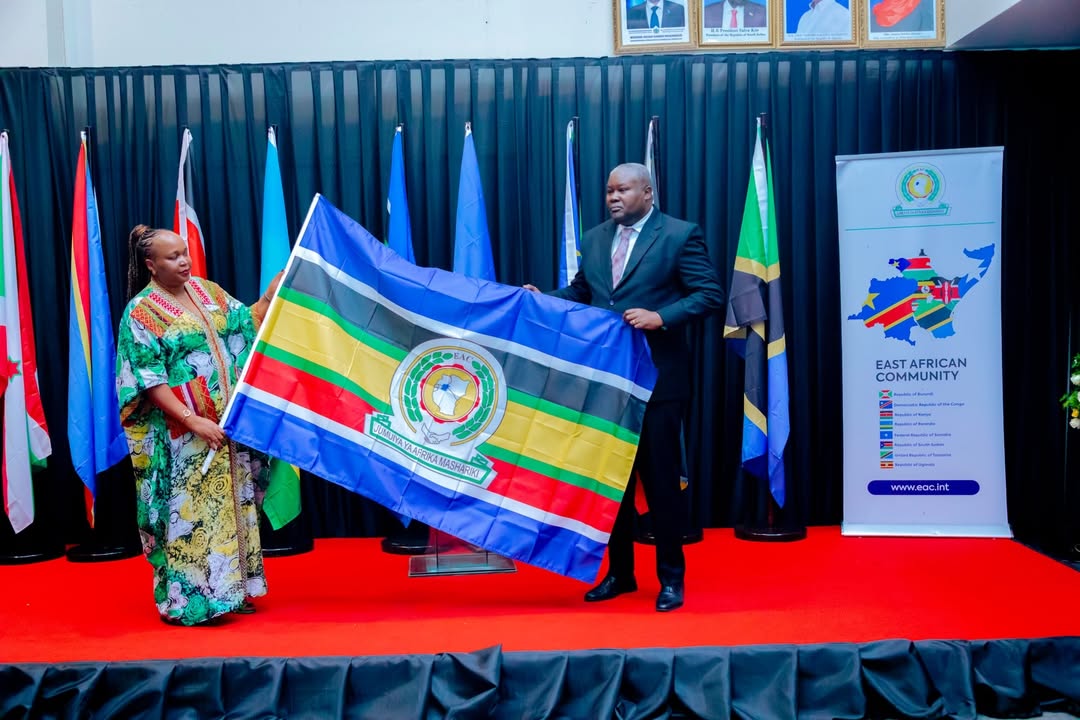 Hon. Veronica M. Nduva handing over to Amb. Stephen P. Mbundi during the EAC Secretary General transition ceremony in Arusha, Tanzania, attended by regional leaders including Hon. James Magode Ikuya.